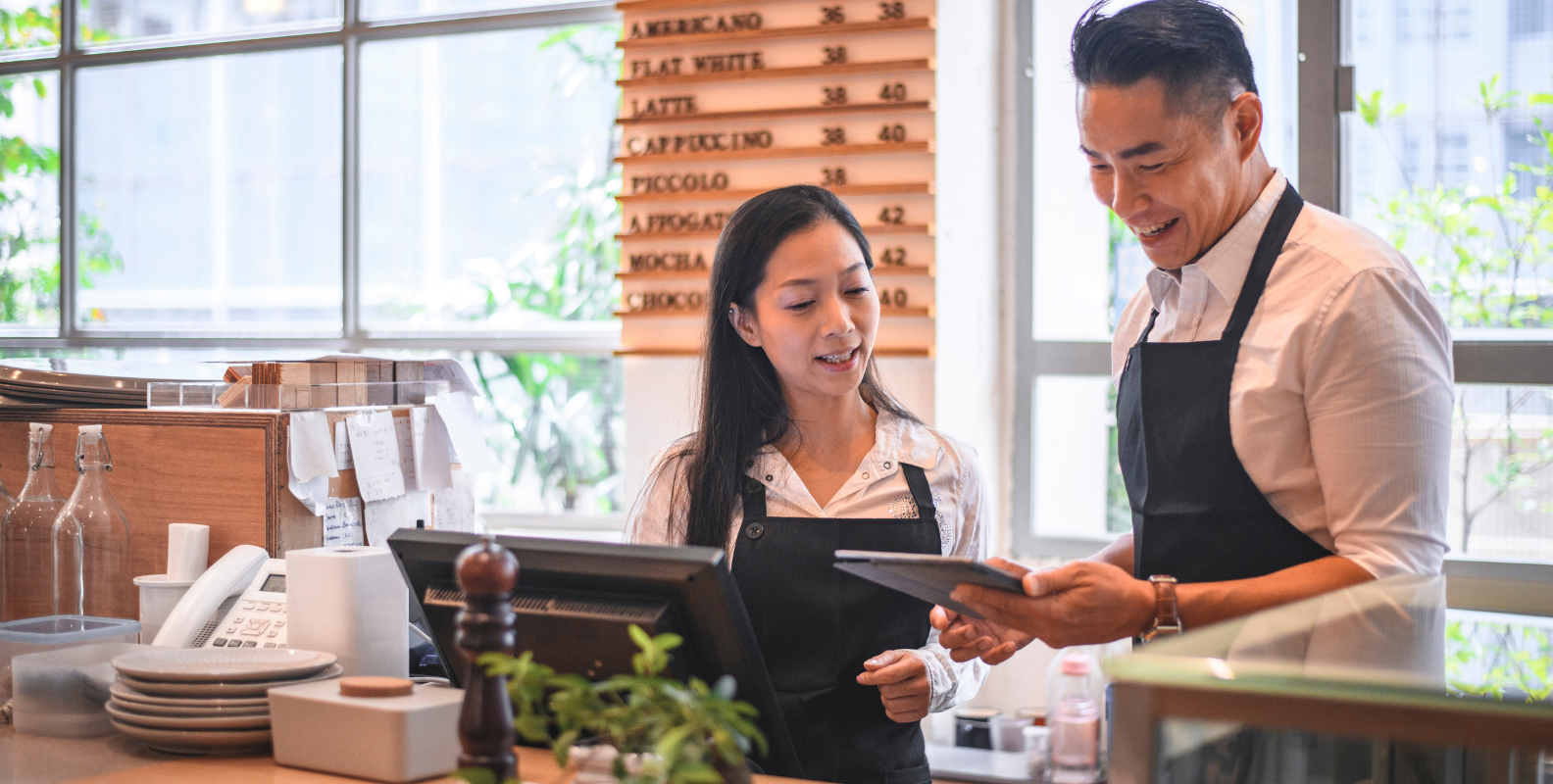 Zwei Mitarbeiter eines Restaurantes stehen vor einer Kasse